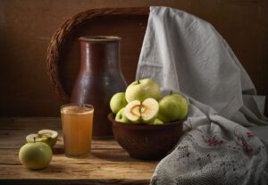 Äpplen, äppelmust och keramikflaska på ett rustikt bord