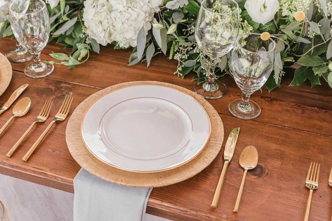 Elegant dukat träbord med tallrikar, bestick, glas och vita blommor