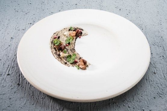 Minimalistisk bistrotallrik med mörkt kött, örter och puré