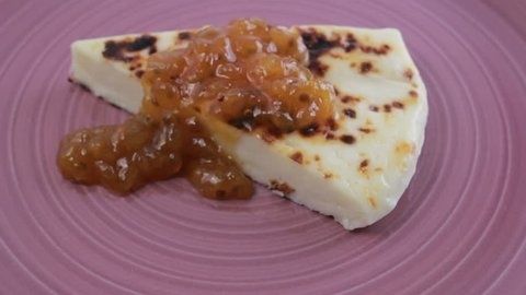 Vit grillad ost med gyllene sylt på ett lila fat
